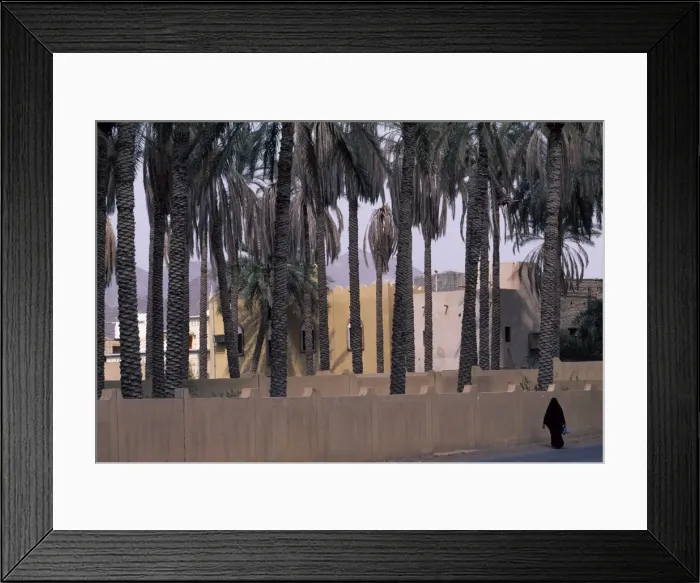 Framed Print : An Omani woman in traditional Arabic dress walks along the road