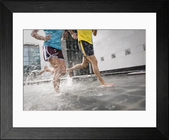Framed Print : A man and woman running barefoot through water