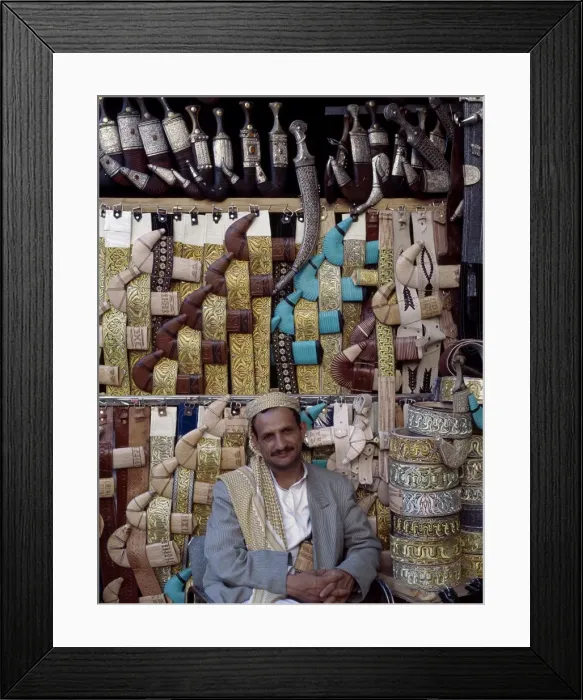 Framed Print : Yemeni trader sells traditional daggers at his stall