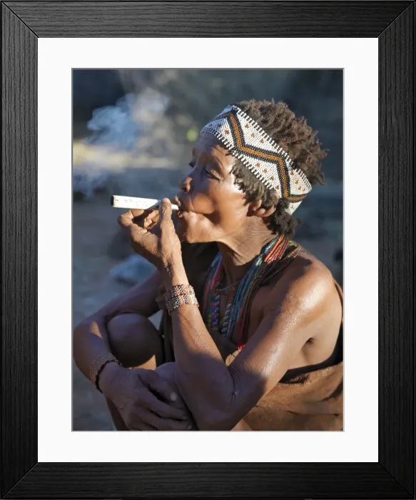 Framed Print : A woman from the N!!S hunter-gatherer band enjoys a smoke Framed Print : A woman from the N!!S hunter-gatherer band enjoys a smoke