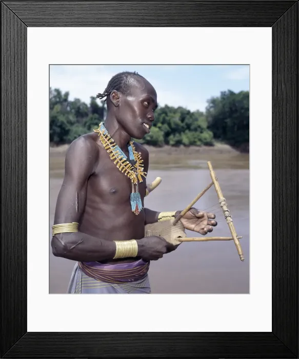 Framed Print : A Karo man with braided hair plays a traditional stringed Framed Print : A Karo man with braided hair plays a traditional stringed