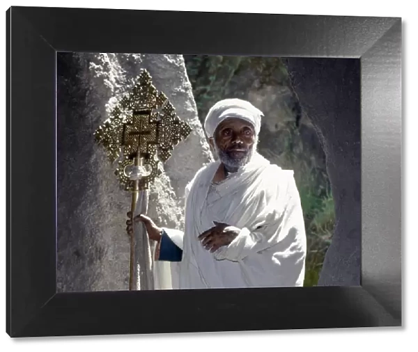 An old Ethiopian Orthodox priest holds a large brass