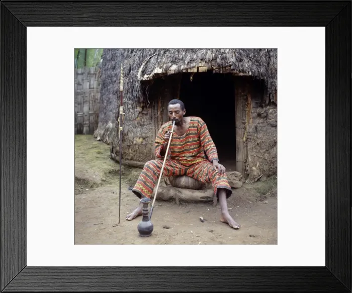 Framed Print : A Dorze man sits outside his home smoking locally-grown Framed Print : A Dorze man sits outside his home smoking locally-grown