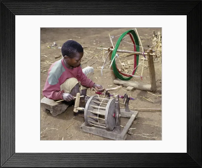 Framed Print : A young Dorze boy winds cotton onto a bobin for his father