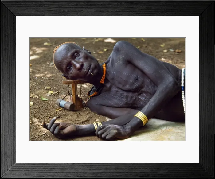 Framed Print : An elder of the Karo tribe rests with his head on his Framed Print : An elder of the Karo tribe rests with his head on his