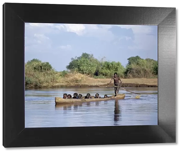 A Dassanech man ferries people in a large dug-out canoe