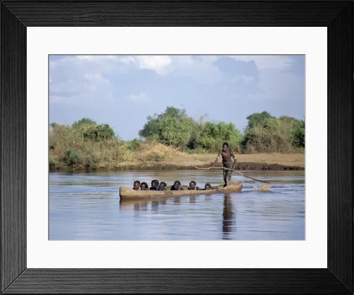 Framed Print : A Dassanech man ferries people in a large dug-out canoe Framed Print : A Dassanech man ferries people in a large dug-out canoe