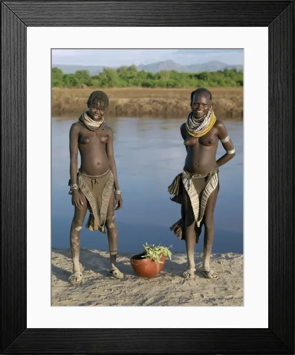 Framed Print : The contrasting leather aprons or skirts of two Nyag atom girls Framed Print : The contrasting leather aprons or skirts of two Nyag atom girls