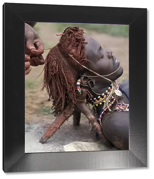 A Samburu warrior has his Ochred hair braided by a friend