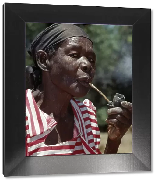 An old Luo lady smoking a traditional clay pipe