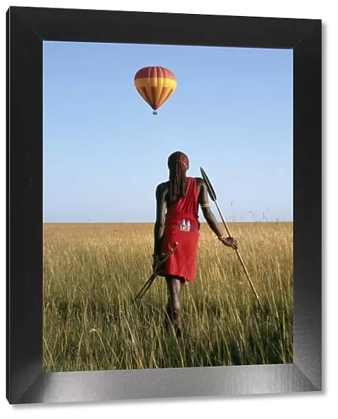 A Msai Warrior watches a hot air balloon float over the Mara plains
