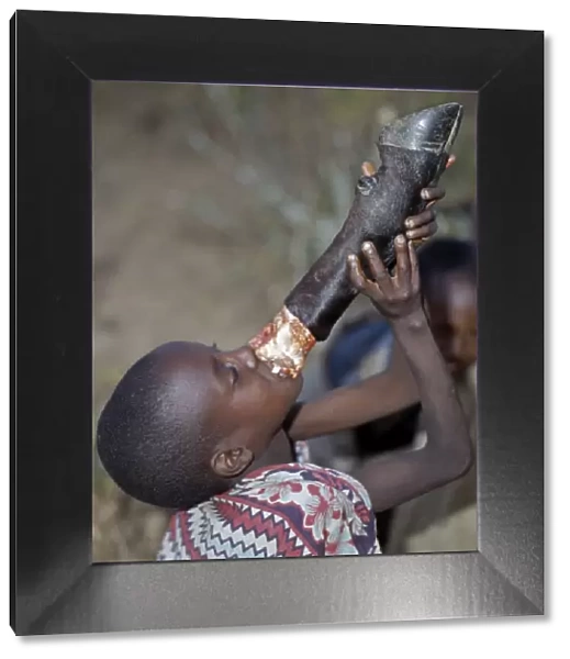 A young Samburu boy sucks marrow straight from the leg bone of a cow