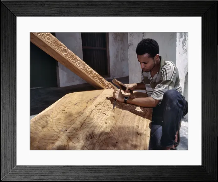 Framed Print : A skilled craftsman with traditional tools carves a Framed Print : A skilled craftsman with traditional tools carves a