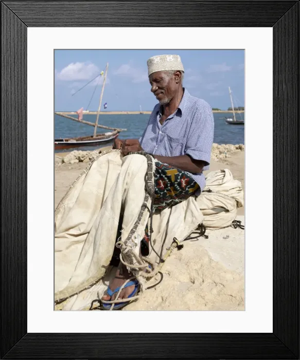 Framed Print : A fisherman repairs the sail of his wooden sailing boat Framed Print : A fisherman repairs the sail of his wooden sailing boat