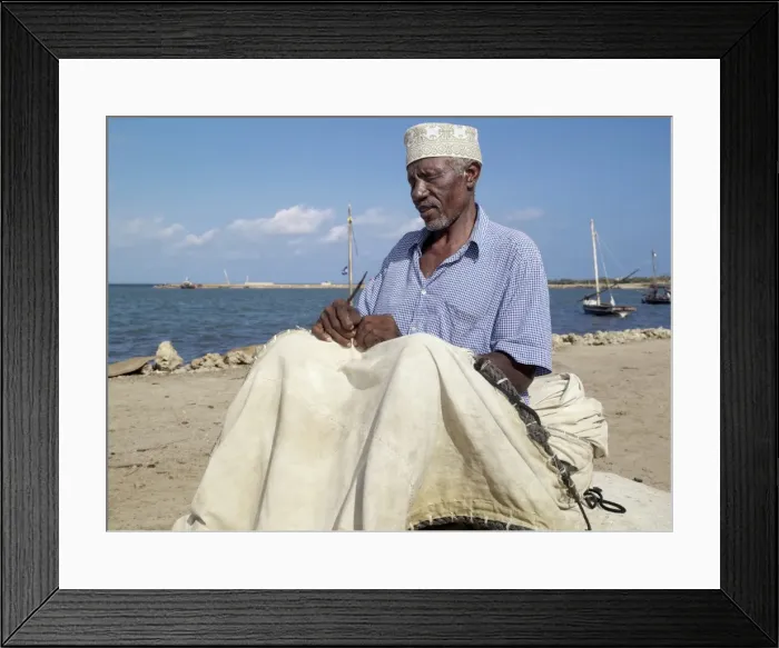 Framed Print : A fisherman repairs the sail of his wooden sailing boat Framed Print : A fisherman repairs the sail of his wooden sailing boat