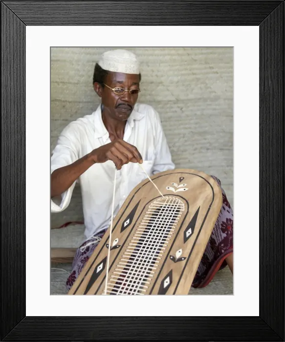 Framed Print : A Lamu man strings the back of a traditional Lamu-style Framed Print : A Lamu man strings the back of a traditional Lamu-style