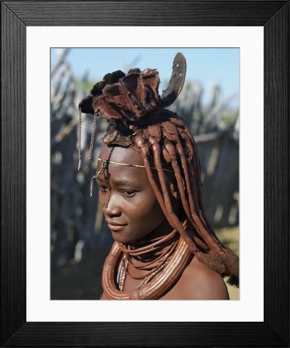 Framed Print : A Himba woman in traditional attire. Her body gleams from a mixture of red ochre Framed Print : A Himba woman in traditional attire. Her body gleams from a mixture of red ochre