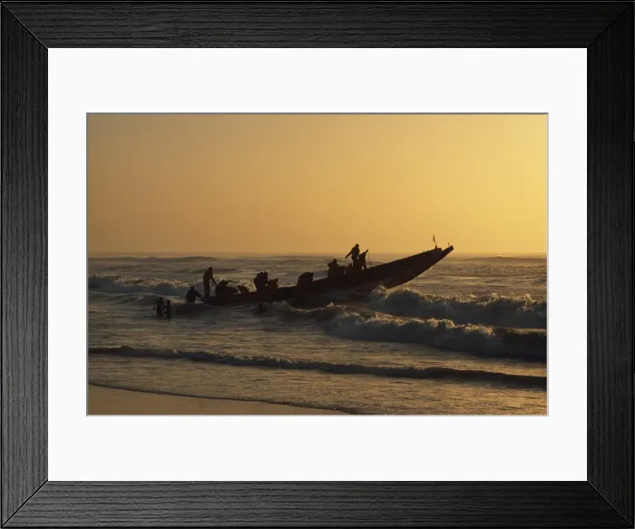 Framed Print : Fishermen launch their boat into the Atlantic Ocean at sunset Framed Print : Fishermen launch their boat into the Atlantic Ocean at sunset