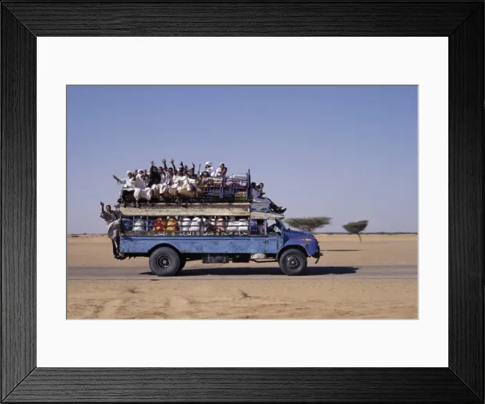 Framed Print : An over-crowded old Bedford bus travels along the main Framed Print : An over-crowded old Bedford bus travels along the main