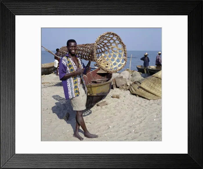Framed Print : A young man carries a wicker fish trap Framed Print : A young man carries a wicker fish trap