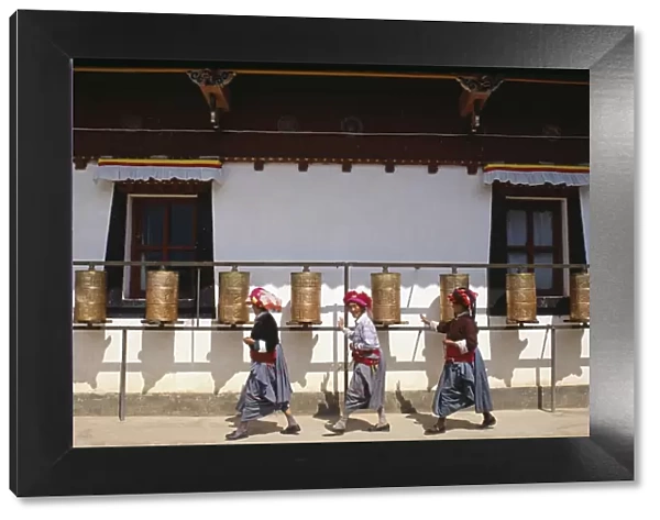 Mosu women push prayer wheels at a small monastery on Liwubi Island