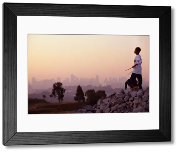 Framed Print : A boy of 11 plays his drum at dawn on a backdrop of Framed Print : A boy of 11 plays his drum at dawn on a backdrop of