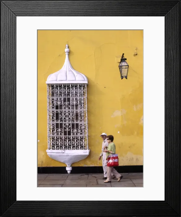 Framed Print : A couple pass a colonial mansion on the Plaza de Armas in Trujillo