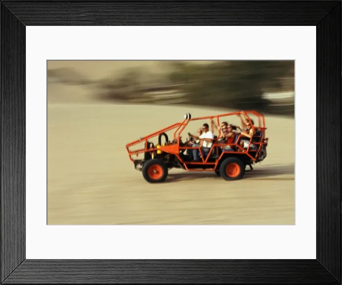 Framed Print : A dune buggy speeds tourists acoss through the sand