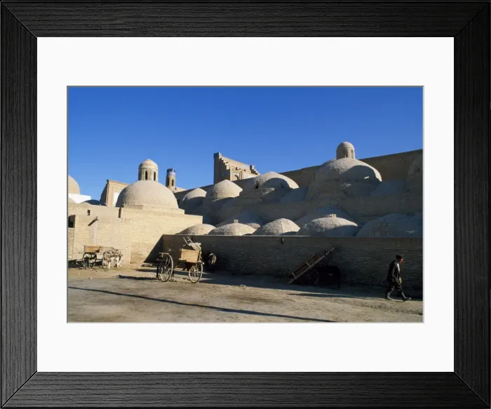 Framed Print : An Uzbek man walks beside the many domed walls of the Ichan Kala Framed Print : An Uzbek man walks beside the many domed walls of the Ichan Kala
