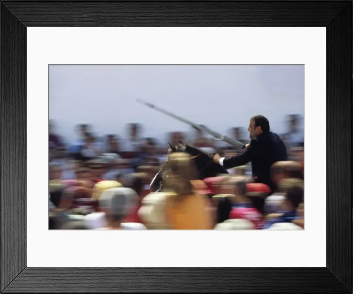 Framed Print : A rider on horseback speeds through the crowd attempting Framed Print : A rider on horseback speeds through the crowd attempting
