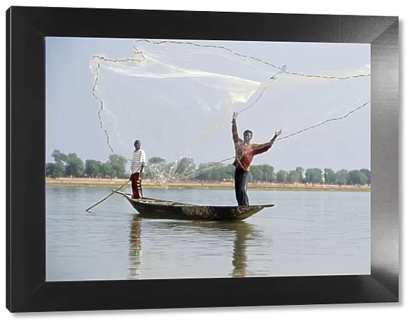 Fisherman cast hand nets on the River Niger from shallow-draught boats