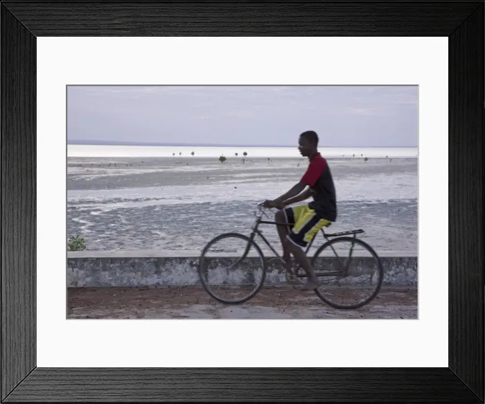 Framed Print : A young man cycling along the sea wall on Ibo Island Framed Print : A young man cycling along the sea wall on Ibo Island
