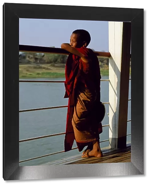 A boy monk gazing out over the rails of a boat on the Irrawaddy River