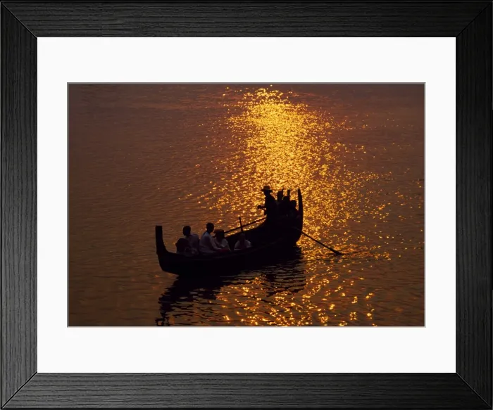 Framed Print : A man rows a local wooden boat across the Irrawaddy River at sunset Framed Print : A man rows a local wooden boat across the Irrawaddy River at sunset
