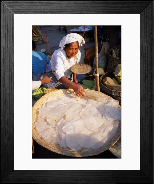Framed Print : A woman sells rice pancakes from her stall at a street market