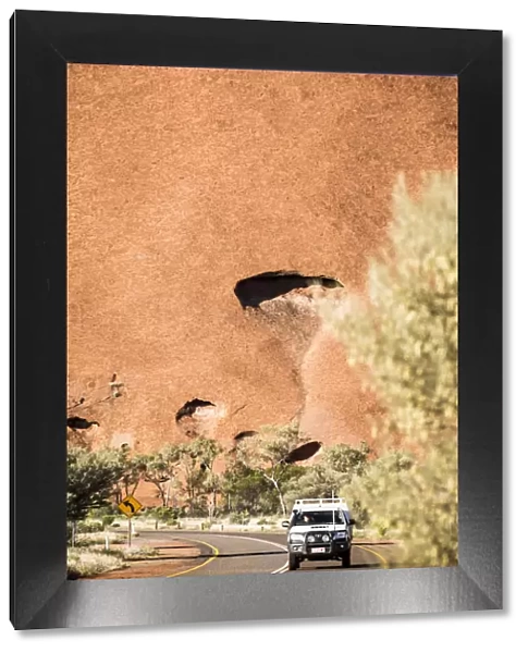 Road and 4x4 with Uluru in background, Australia