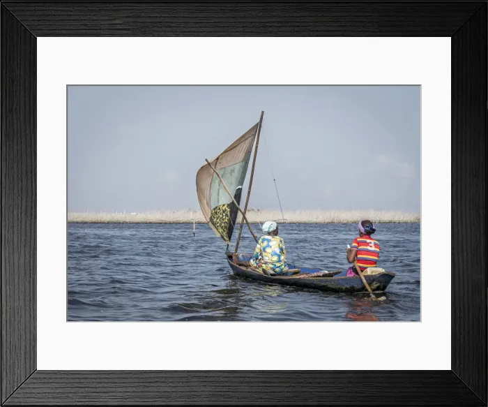 Framed Print : two colorfully dressed local women in wooden sailing canoe on the lake Framed Print : two colorfully dressed local women in wooden sailing canoe on the lake