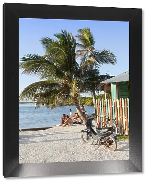 Central America, Belize, Belize district, Caye Caulker, tourists sit on the tiny beach
