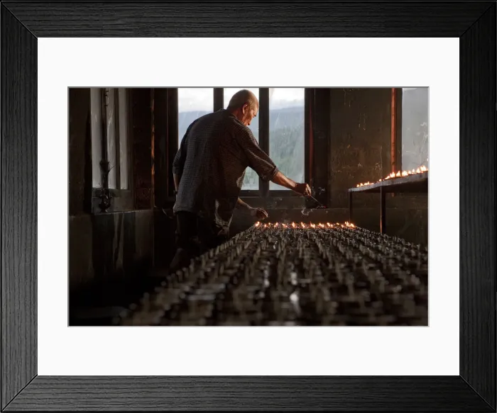 Framed Print : A man lighting candles in a temple in Bhutan Framed Print : A man lighting candles in a temple in Bhutan