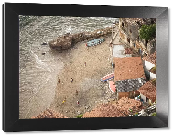 Brazil, Bahia, Salvador, locals playing football on the beach in a favela (slum community)