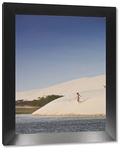 South America, Brazil, Maranhao, a woman in a bikini descends a dune in the Lagoa
