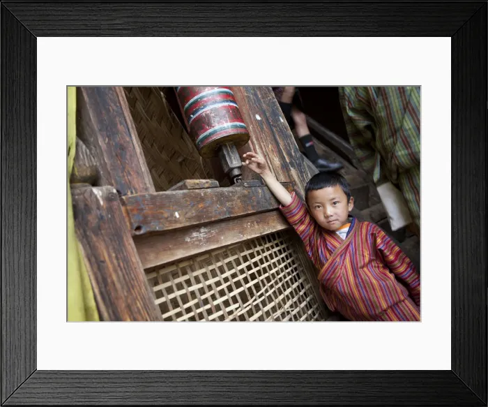 Framed Print : A young boy playing with a prayer wheel in the Thangbi Mani monastery in Bhutan Framed Print : A young boy playing with a prayer wheel in the Thangbi Mani monastery in Bhutan