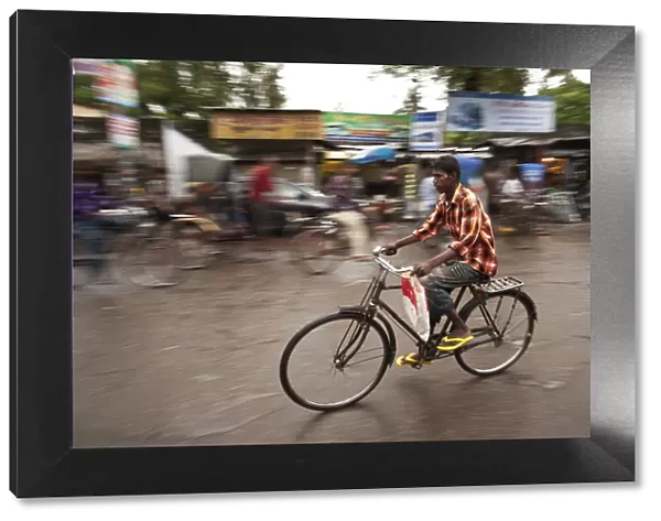 Jessore, Bangladesh. A man cycles to work through the centre of town