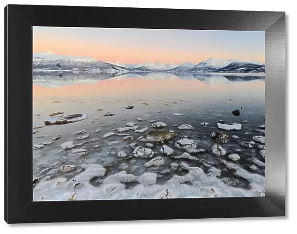 Cloudless sunrise with ice covering the stones on the shore of Balsfjorden. Markenes