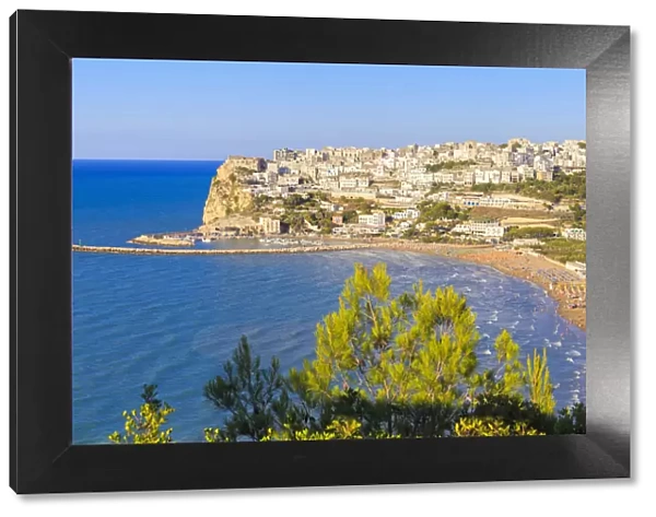 The sun illuminates the ancient town of Peschici and its beach full of tourists. Apulia