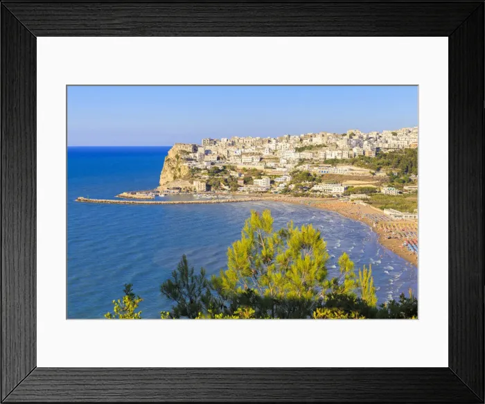 Framed Print : The sun illuminates the ancient town of Peschici and its beach full of tourists. Apulia