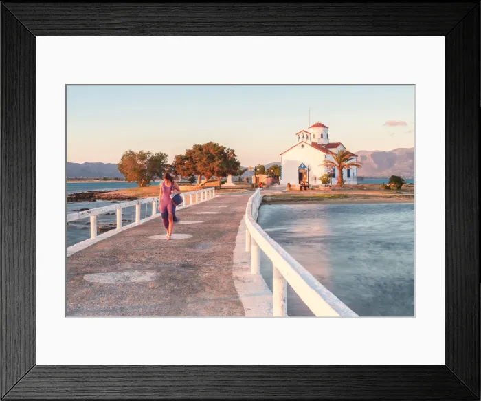 Framed Print : A woman crossing the bridge that link Elafonissos island with the orthodox church of St Framed Print : A woman crossing the bridge that link Elafonissos island with the orthodox church of St