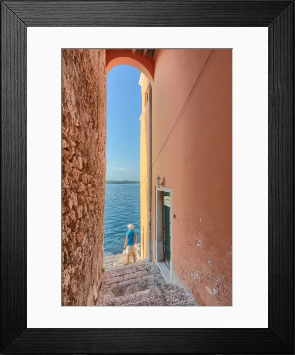 Framed Print : small arched opening overlooking the sea along the streets of Rovinj, tourist admires Framed Print : small arched opening overlooking the sea along the streets of Rovinj, tourist admires