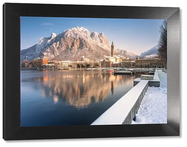 Snowy lakefront of Lecco and San Martino Mountain reflected in Como lake, Lecco province