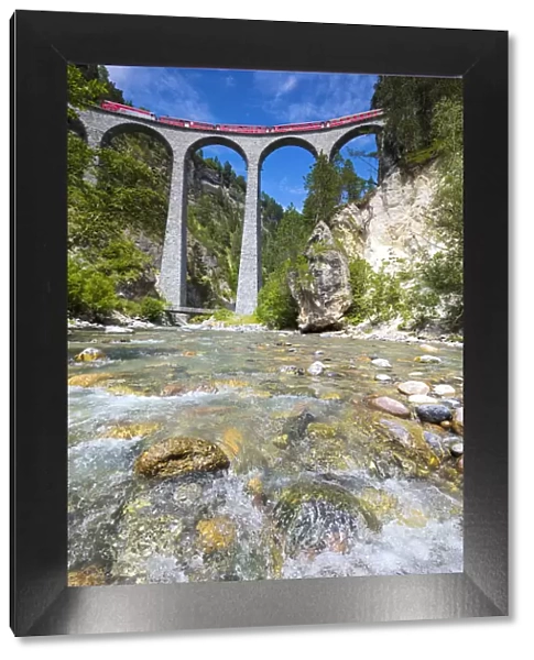 The alpine stream frames the Bernina Express train on Landwasser Viadukt Filisur Albula